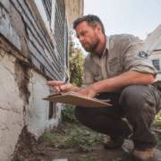Foundation repair contractor inspecting exterior cracks and estimating foundation repair cost