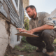 Foundation repair contractor inspecting exterior cracks and estimating foundation repair cost