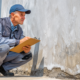 Professional foundation repair contractor inspecting concrete foundation wall with clipboard determining which common foundation repair method to use